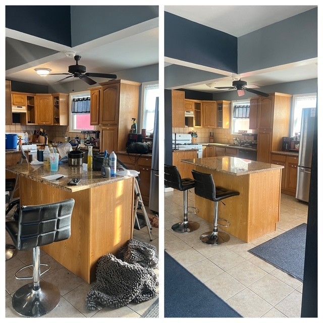 Kitchen interior with wood cabinets, black bar stools, and a central island under ceiling fans