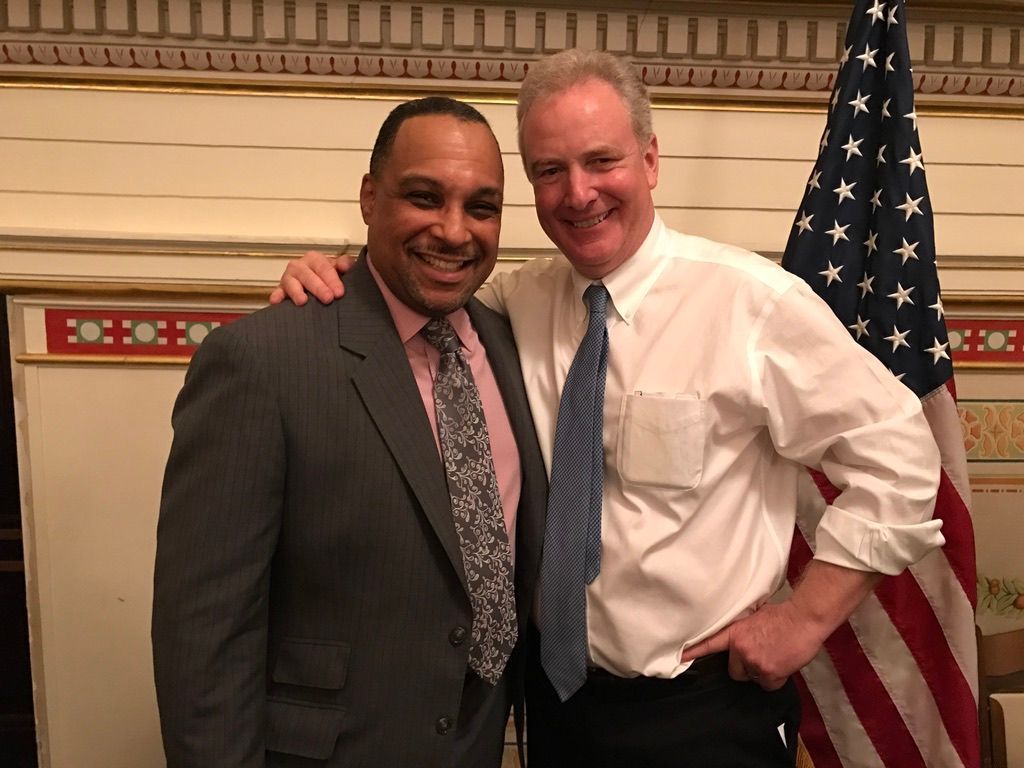 Two men are posing for a picture in front of an american flag.
