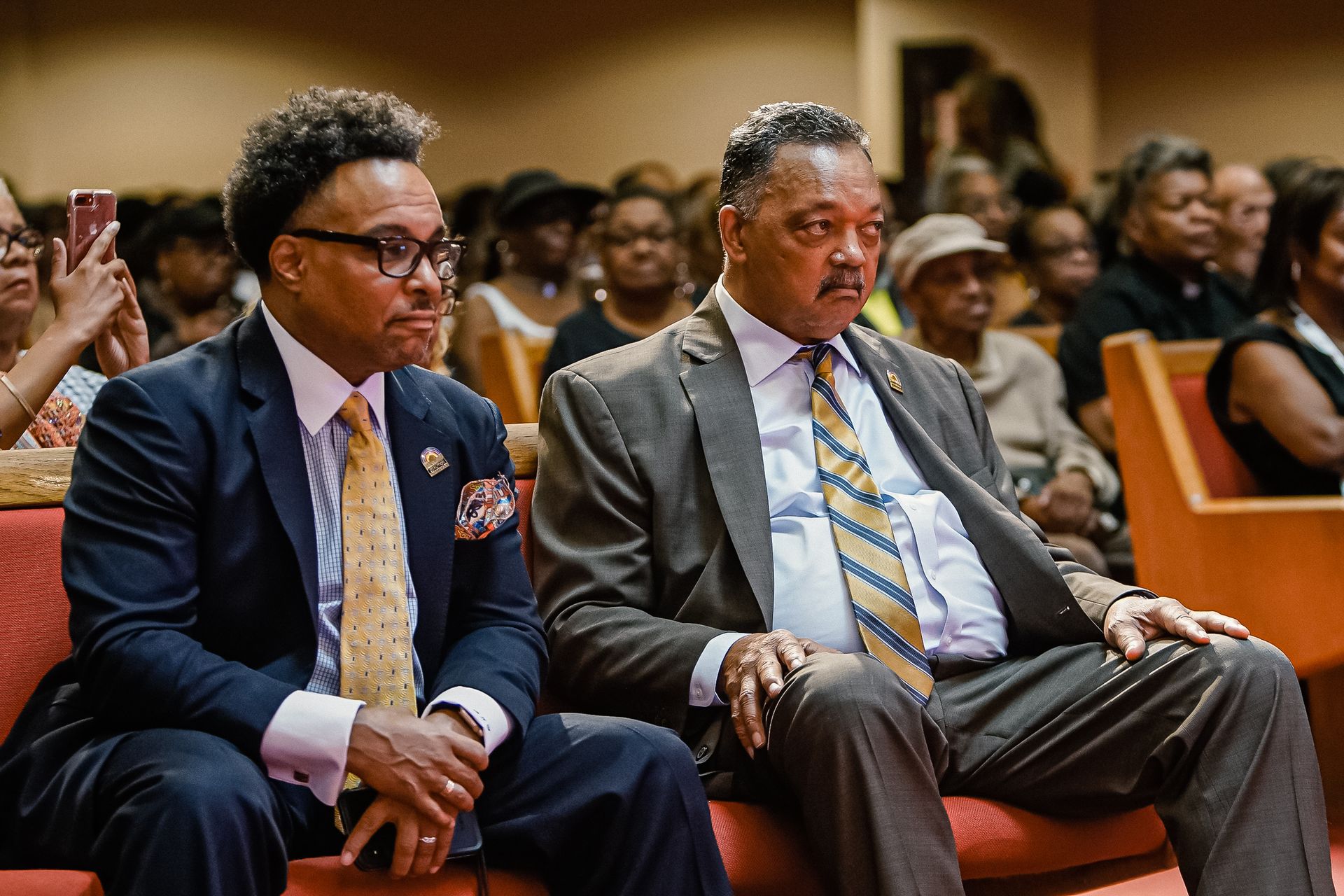Two men in suits and ties are sitting in a church.