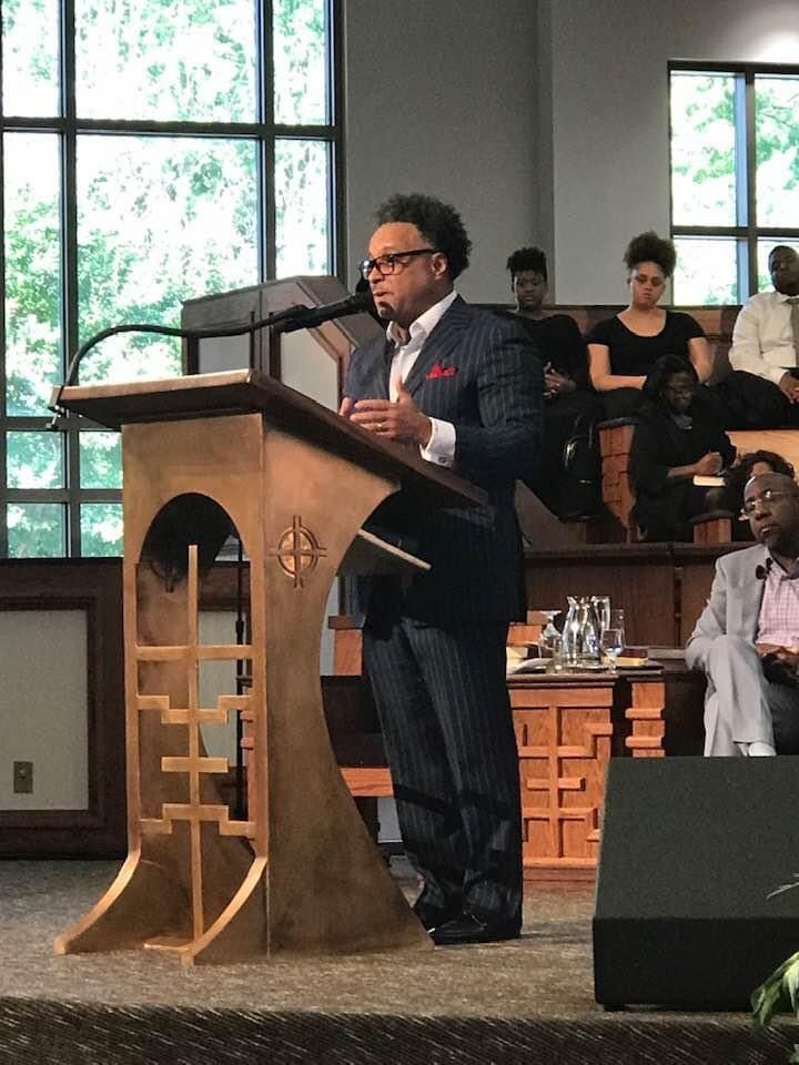 A man in a suit is standing at a podium giving a speech.