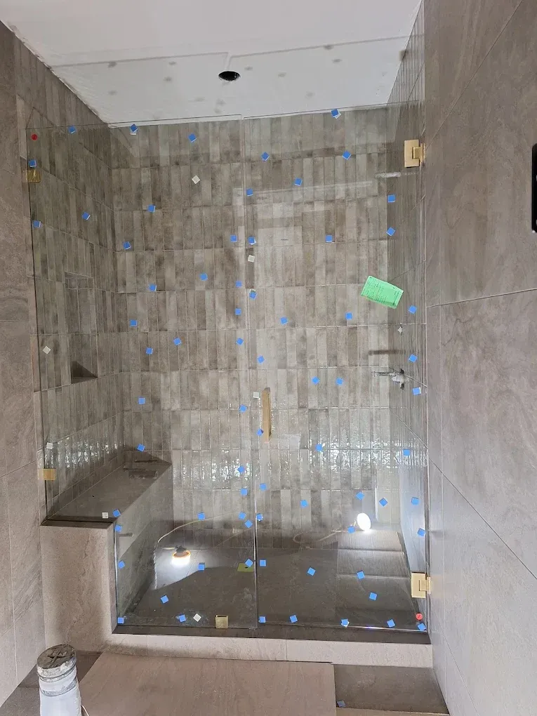 Empty tiled shower stall with a built-in bench and a small green tag on the back wall.