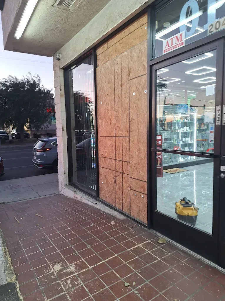 Storefront with boarded-up glass door and windows on a sidewalk at dusk