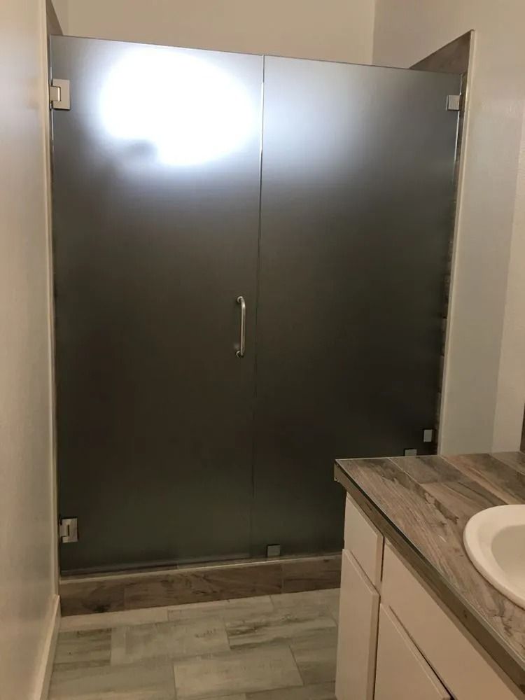 Stall bathroom with frosted glass doors and a sink counter in the foreground