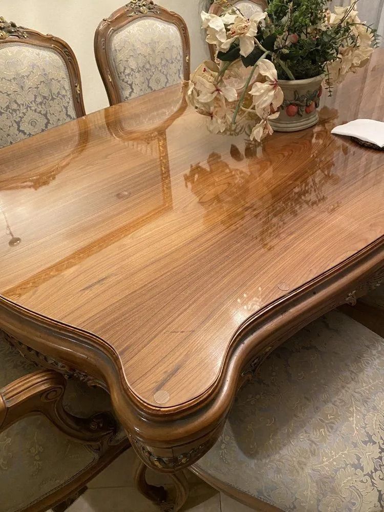 Polished wooden dining table with carved chairs and a floral centerpiece in a formal room