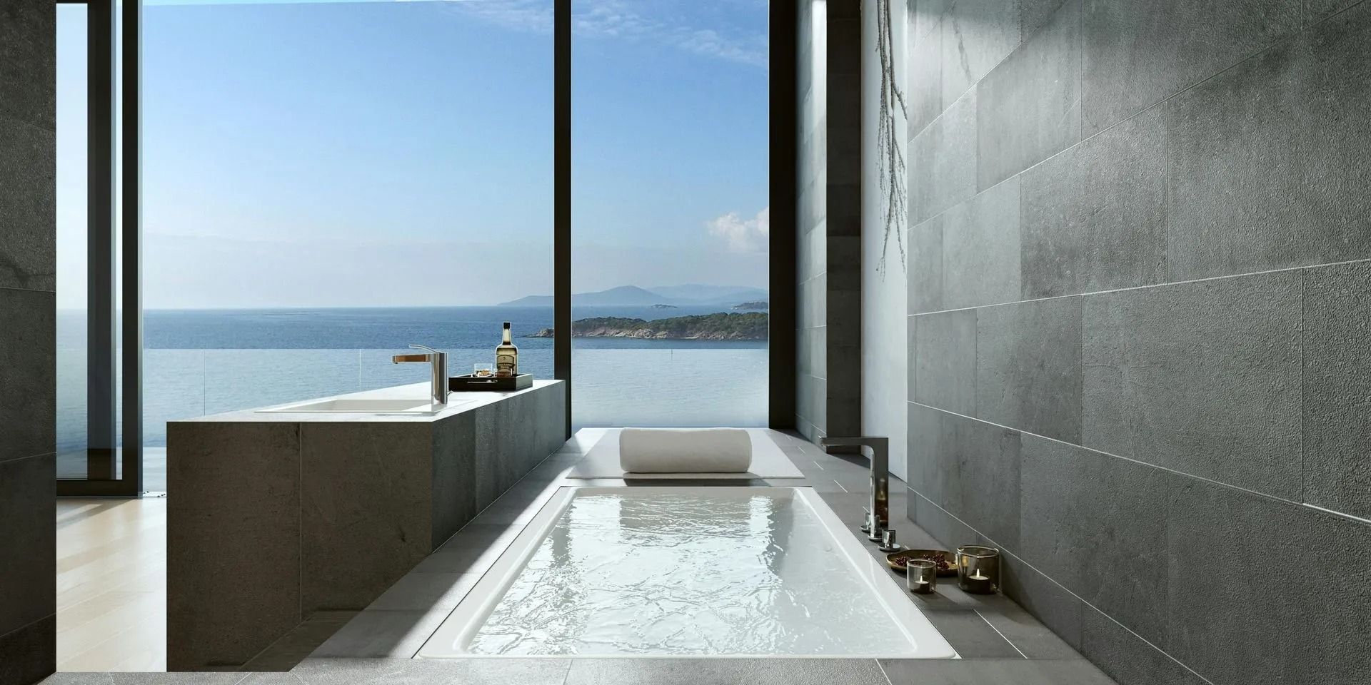 Modern bathroom with a long soaking tub, dark stone walls, and ocean view through large windows