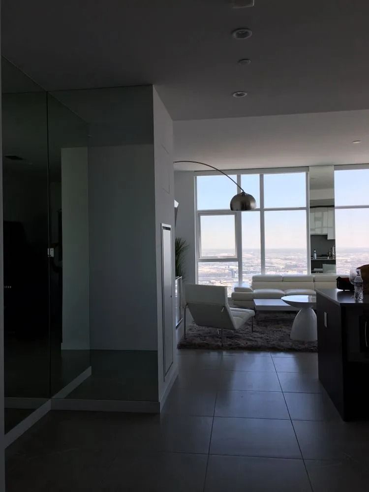 Modern apartment living room with large windows, dining table, and city view