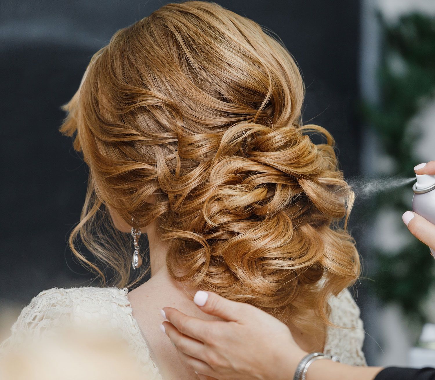 stylist makes the bride hairstyle using spray lacquer fixing