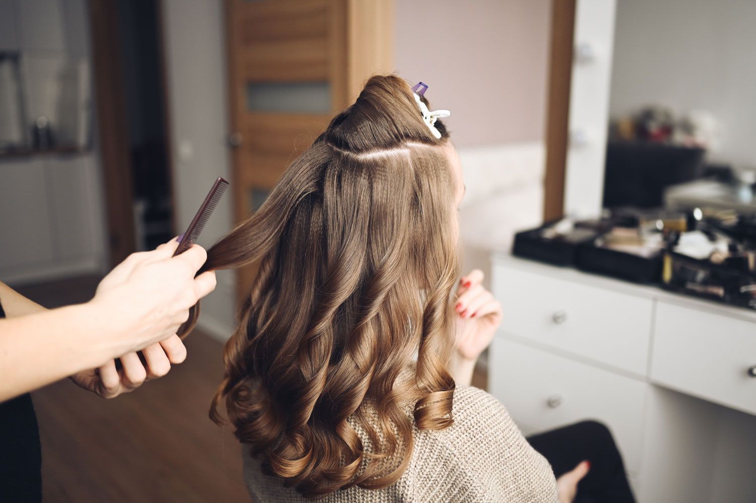 Hair stylist prepares woman makes curls hairstyle with curling iron