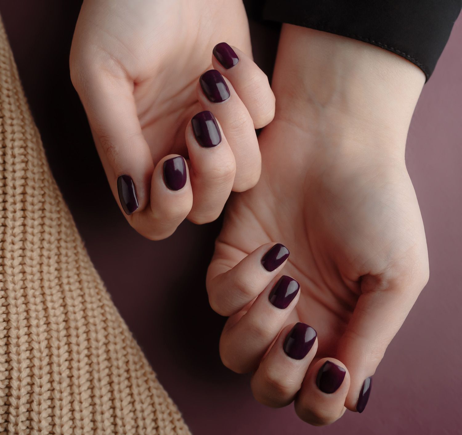 Woman hands with beautiful manicure near a beige wool material