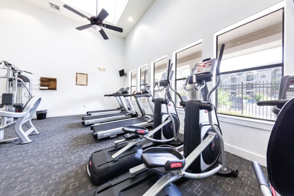 a gym with a lot of exercise equipment and a ceiling fan at Marquis at Katy in Katy, TX.