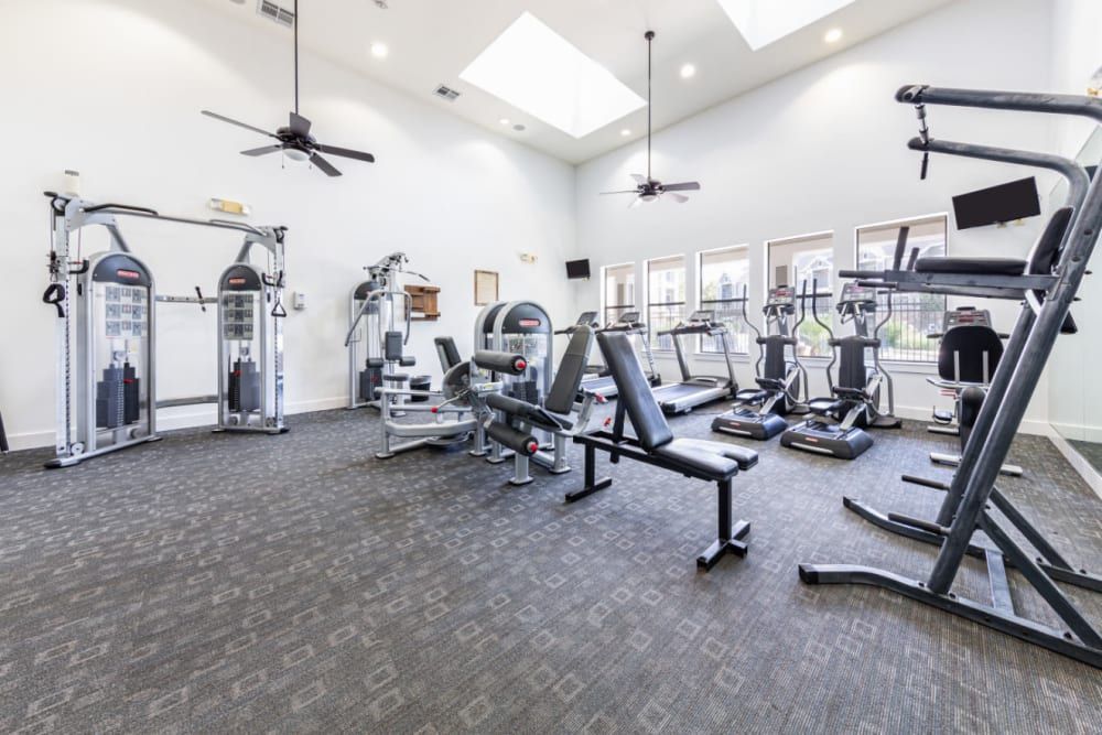 a large gym with a lot of equipment and a ceiling fan at Marquis at Katy in Katy, TX.