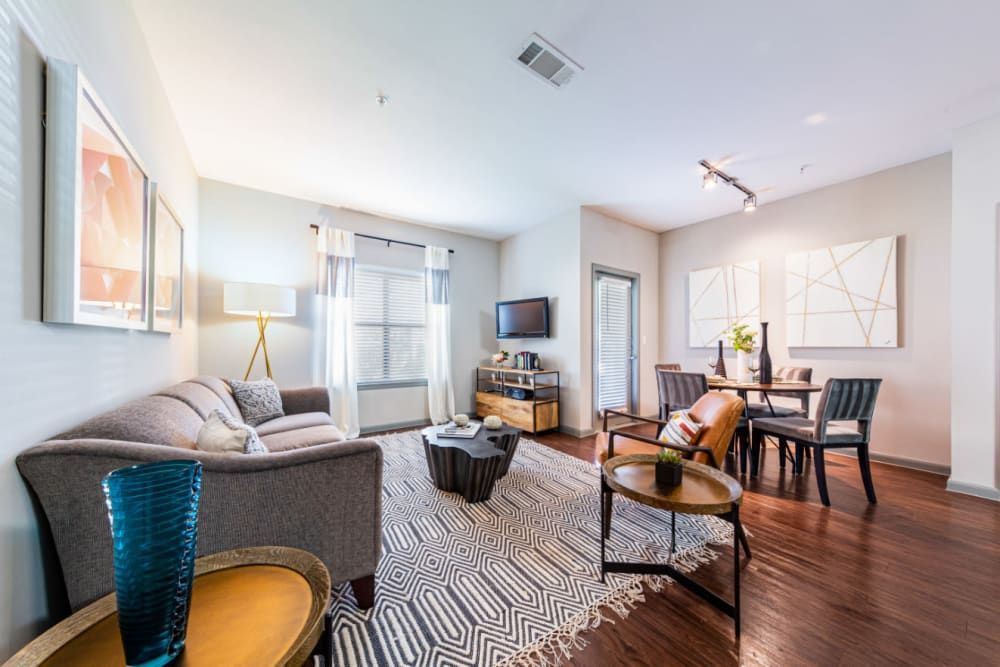 a living room with a couch, table, chairs, and a television at Marquis at Katy in Katy, TX.