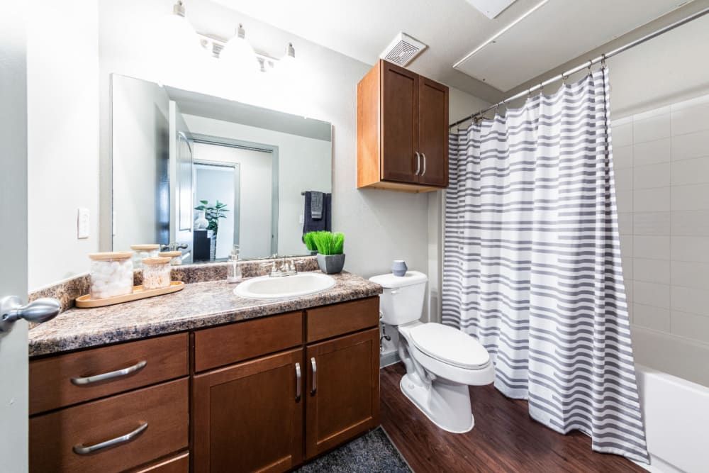 a bathroom with a toilet, sink, mirror, and shower curtain at Marquis at Katy in Katy, TX.
