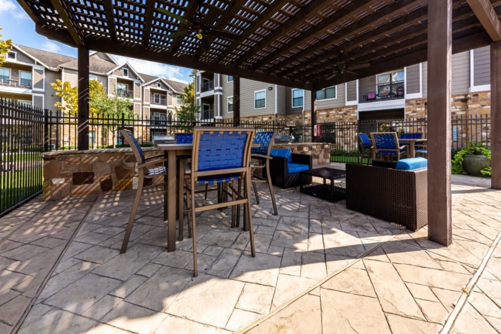 a patio with a table and chairs under a pergola at Marquis at Katy in Katy, TX.