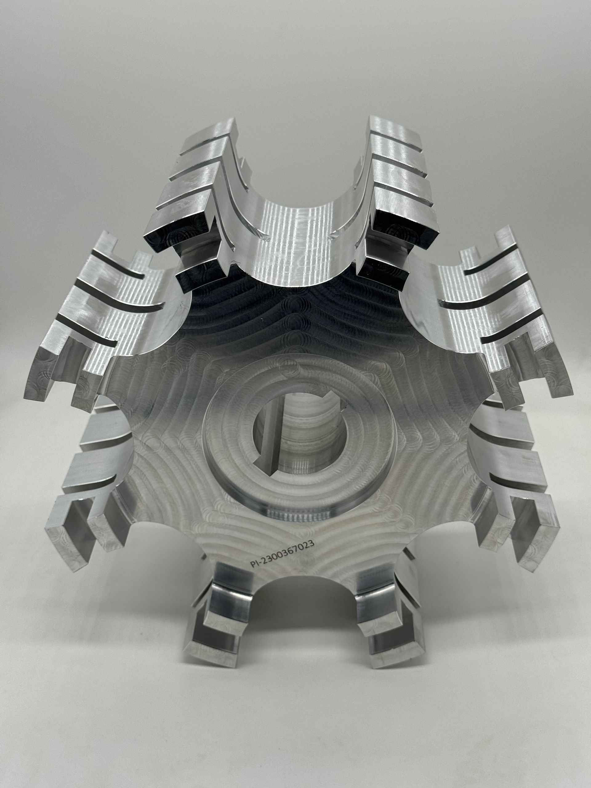 A metallic, six-spoked hub component with machined ridges, centered on a plain white background.