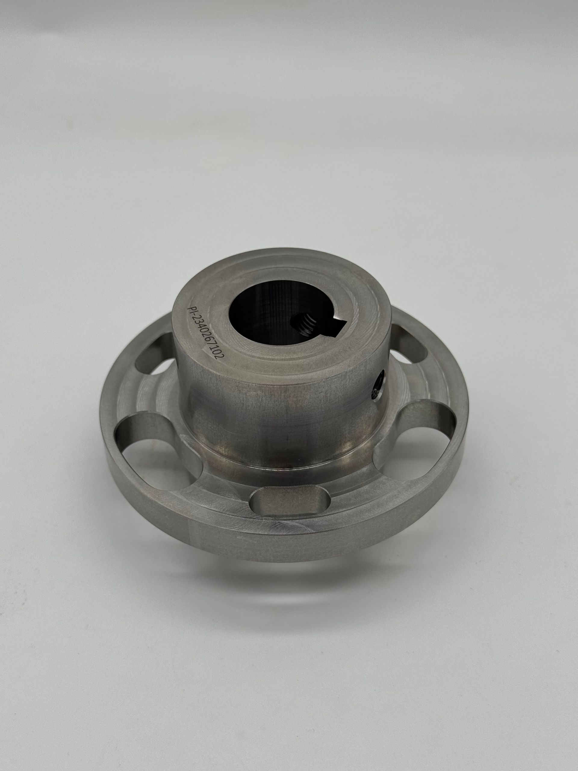 A gray, cylindrical metal machine hub with a keyway and circular cutouts on the flange, set against a plain background.