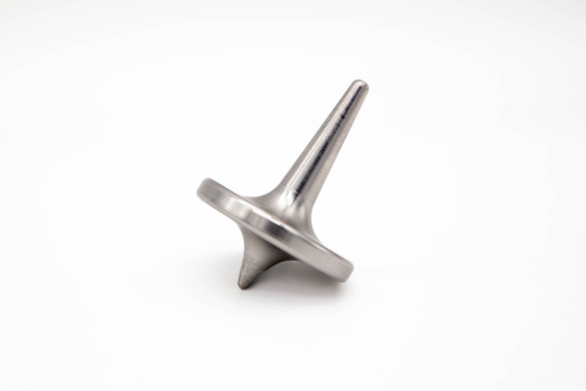 Metallic spinning top, tilted on a white background.