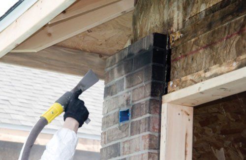 Worker Cleaning Smoky Bricks — Linn Grove, IA — Hare Painting & Sandblasting