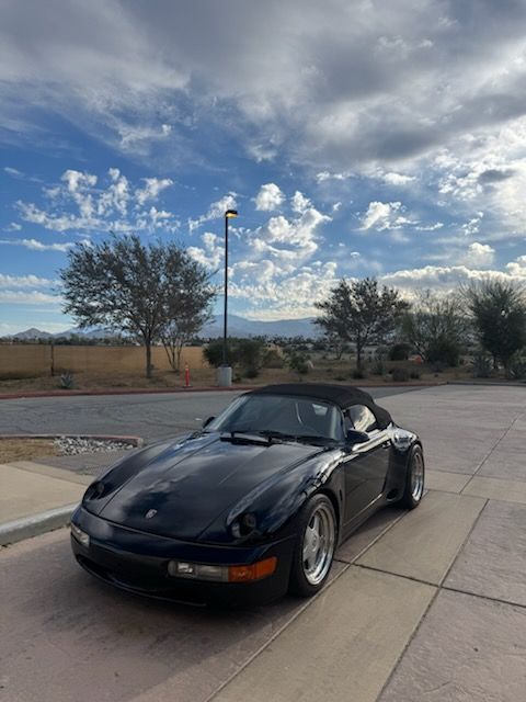 Black convertible sports car parked on a street under a cloudy sky