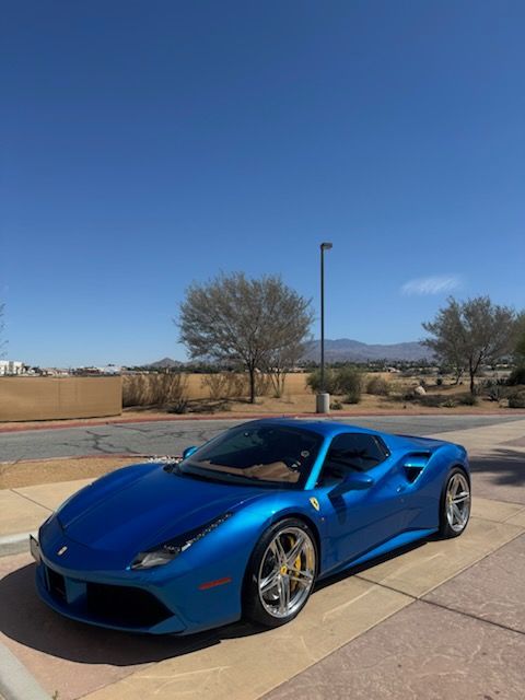Blue sports car parked outdoors under a clear sky.