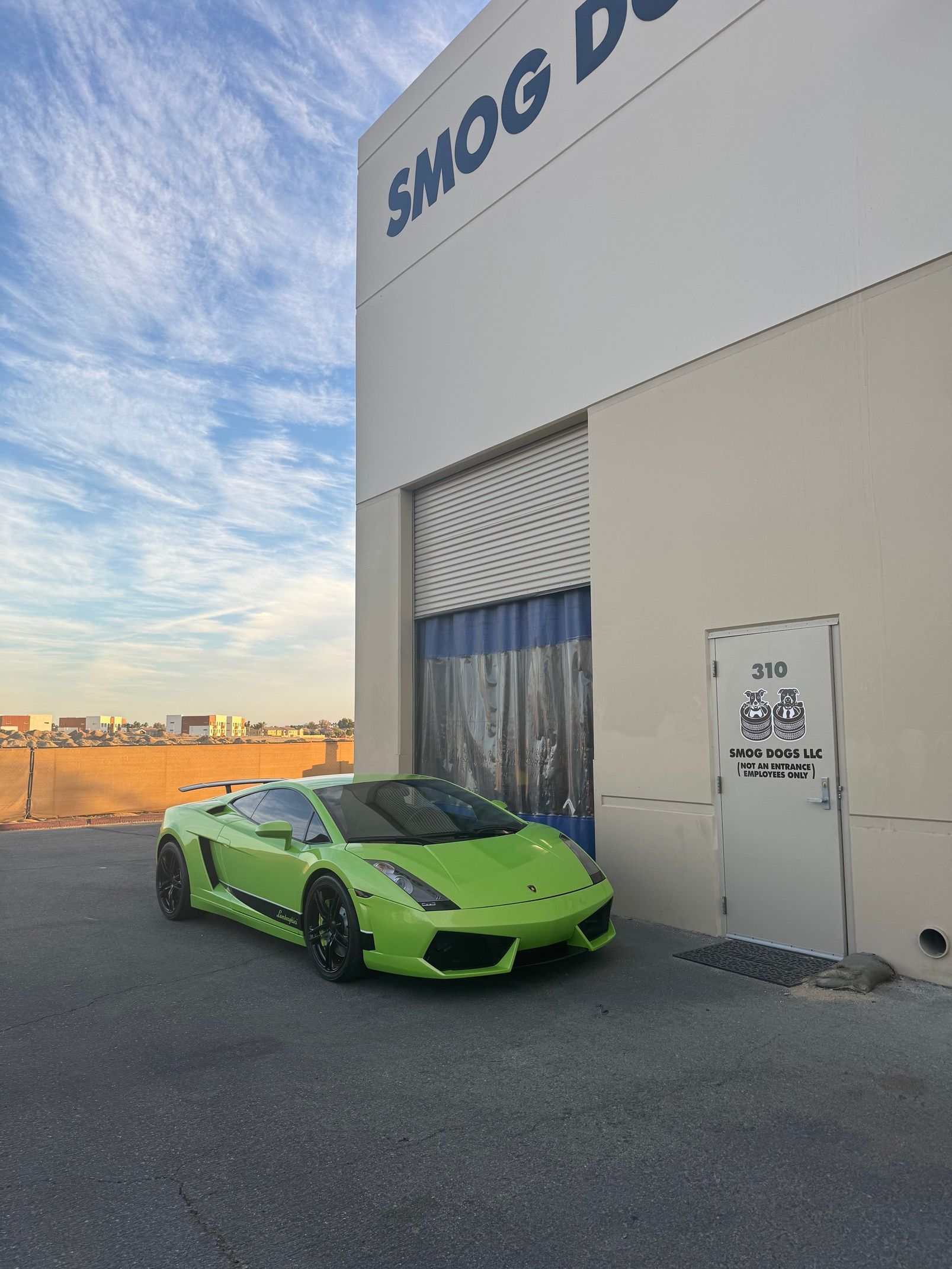 Bright green sports car parked by a warehouse loading door at sunset