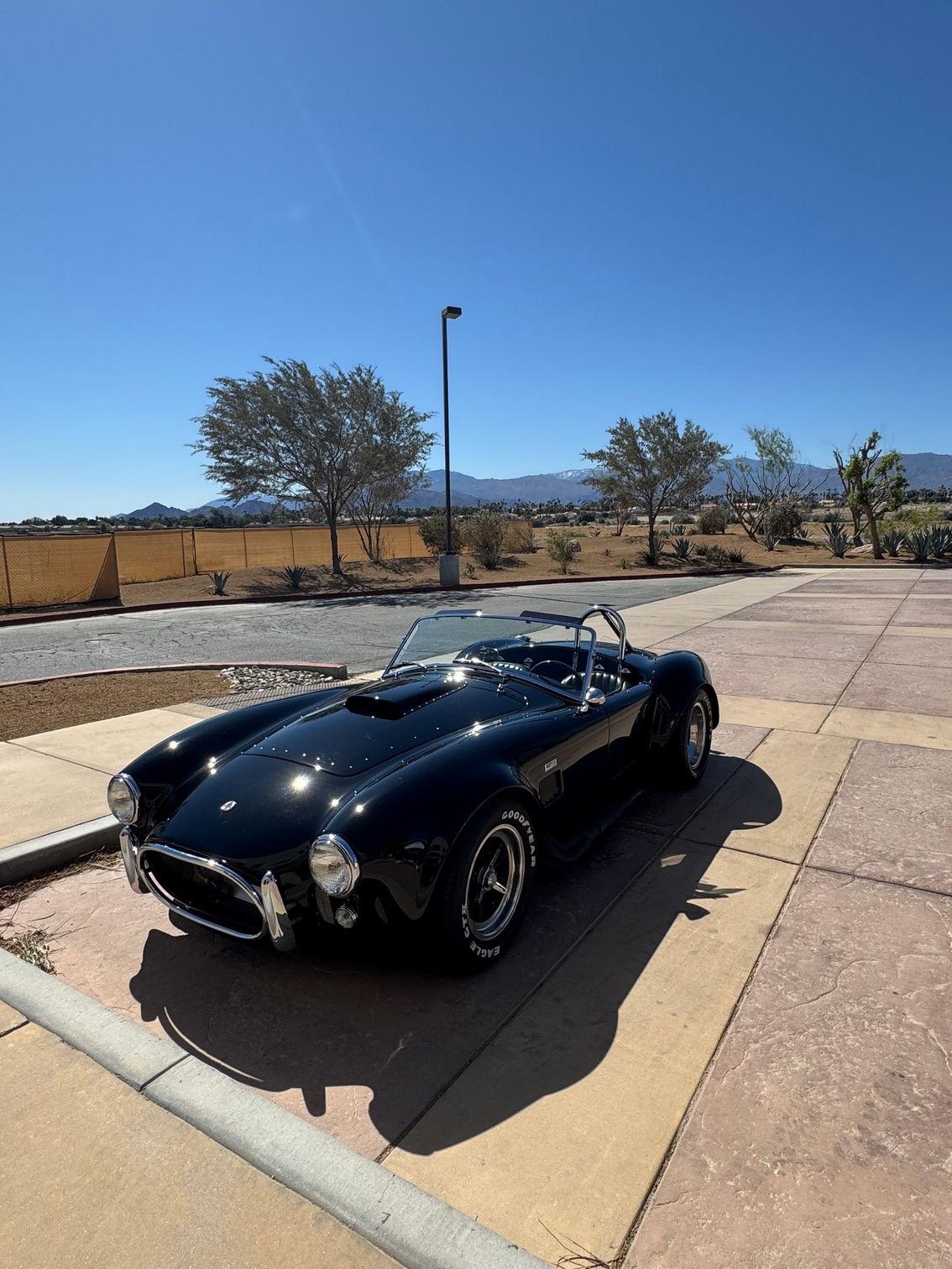 Black vintage sports car parked on a sunny street under a clear blue sky
