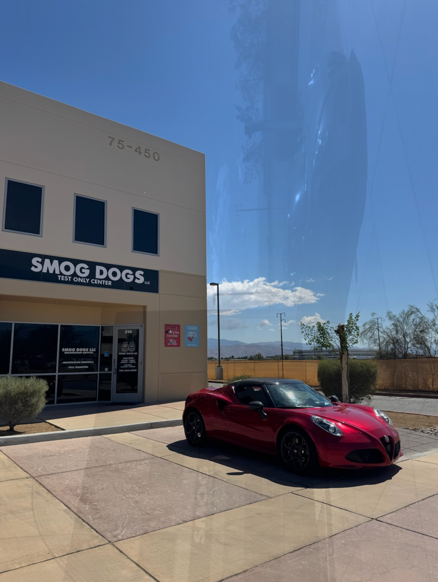 Red sports car parked outside SMOG DOGS storefront on a sunny day