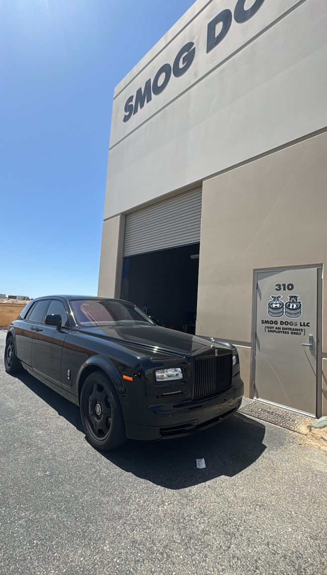 Black luxury SUV parked outside a warehouse-style building with an open garage door.