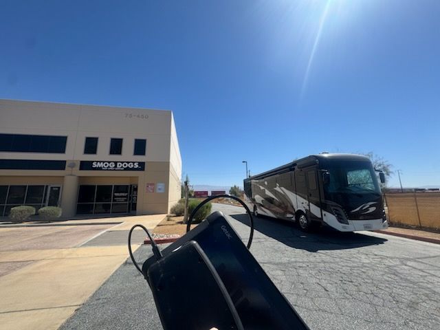 Large black-and-white bus parked outside a building on a sunny day.