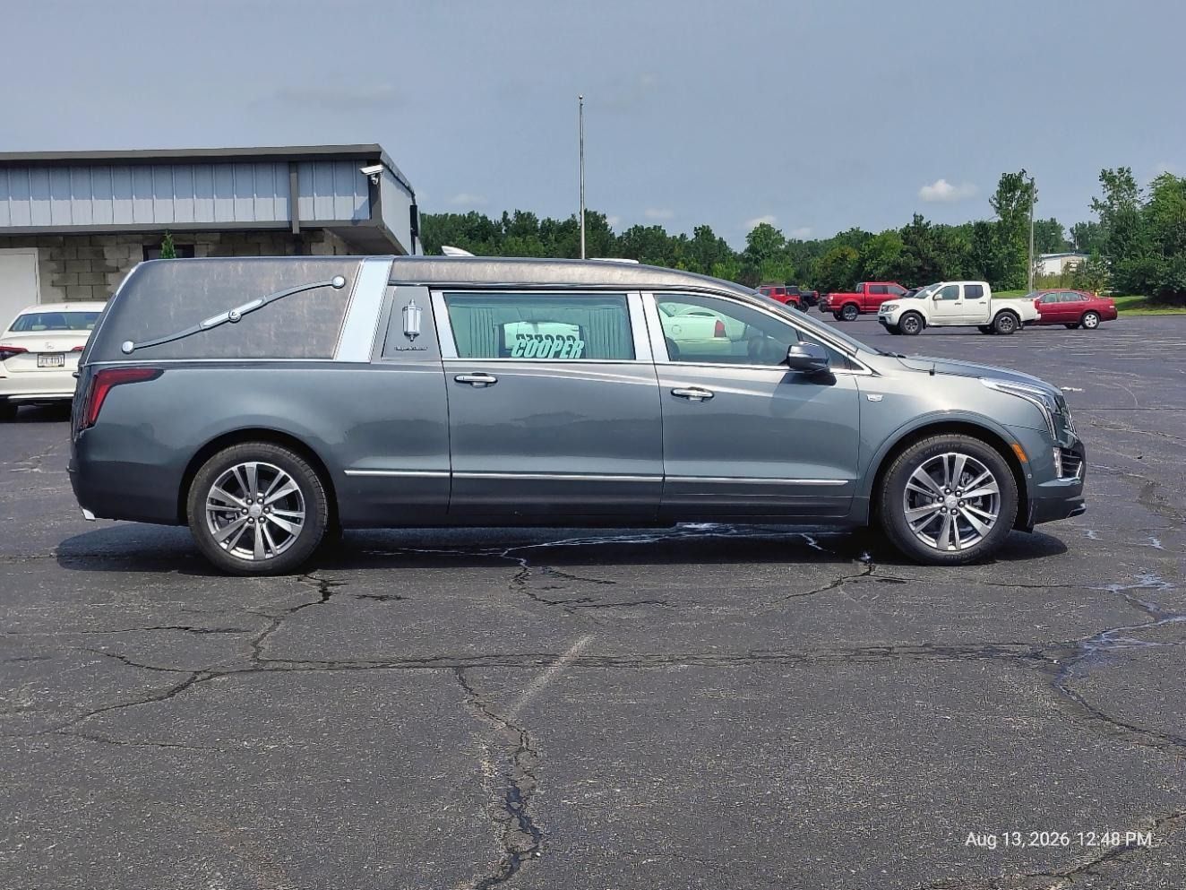 Gray hearse parked in a lot, side view on cracked pavement