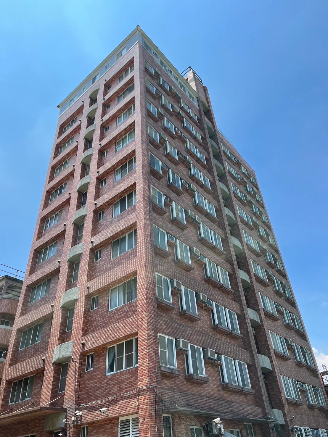 抬頭看著一座高高的磚造建築，背景是藍天。