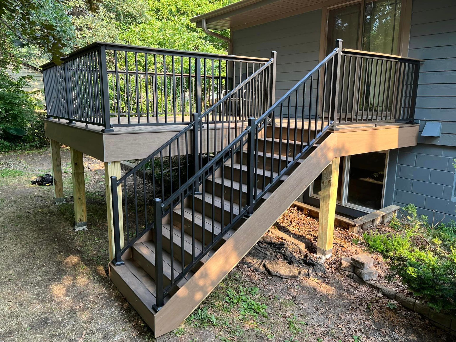A deck with stairs leading up to it and a black railing.