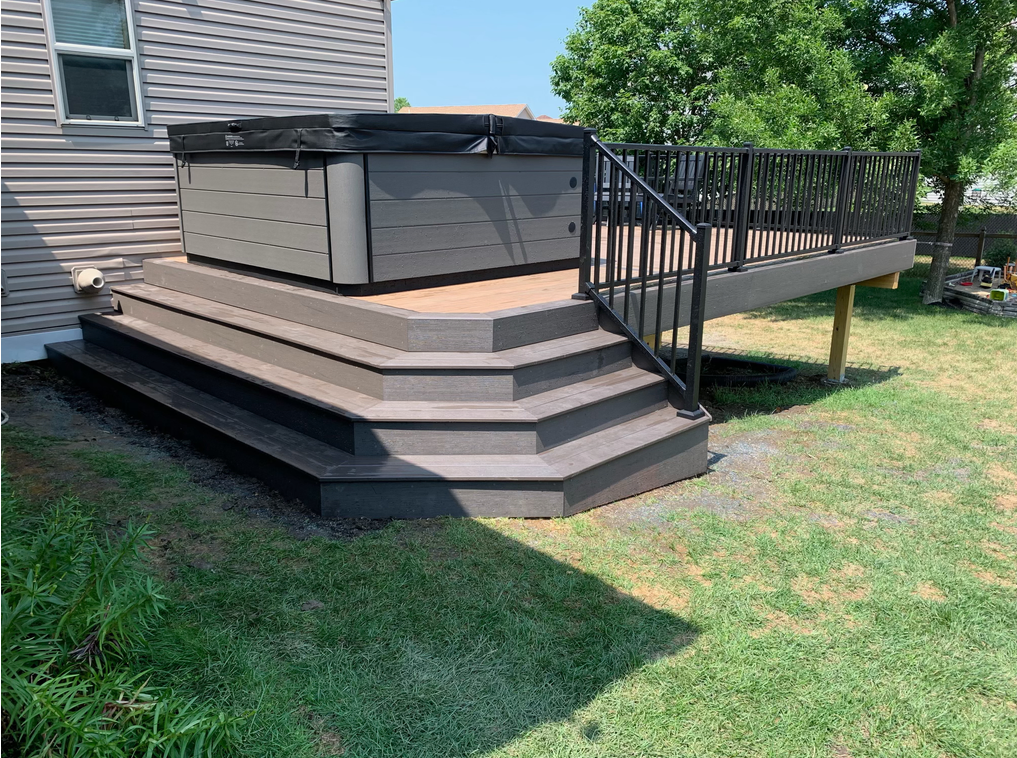 A deck with stairs and a hot tub on top of it.