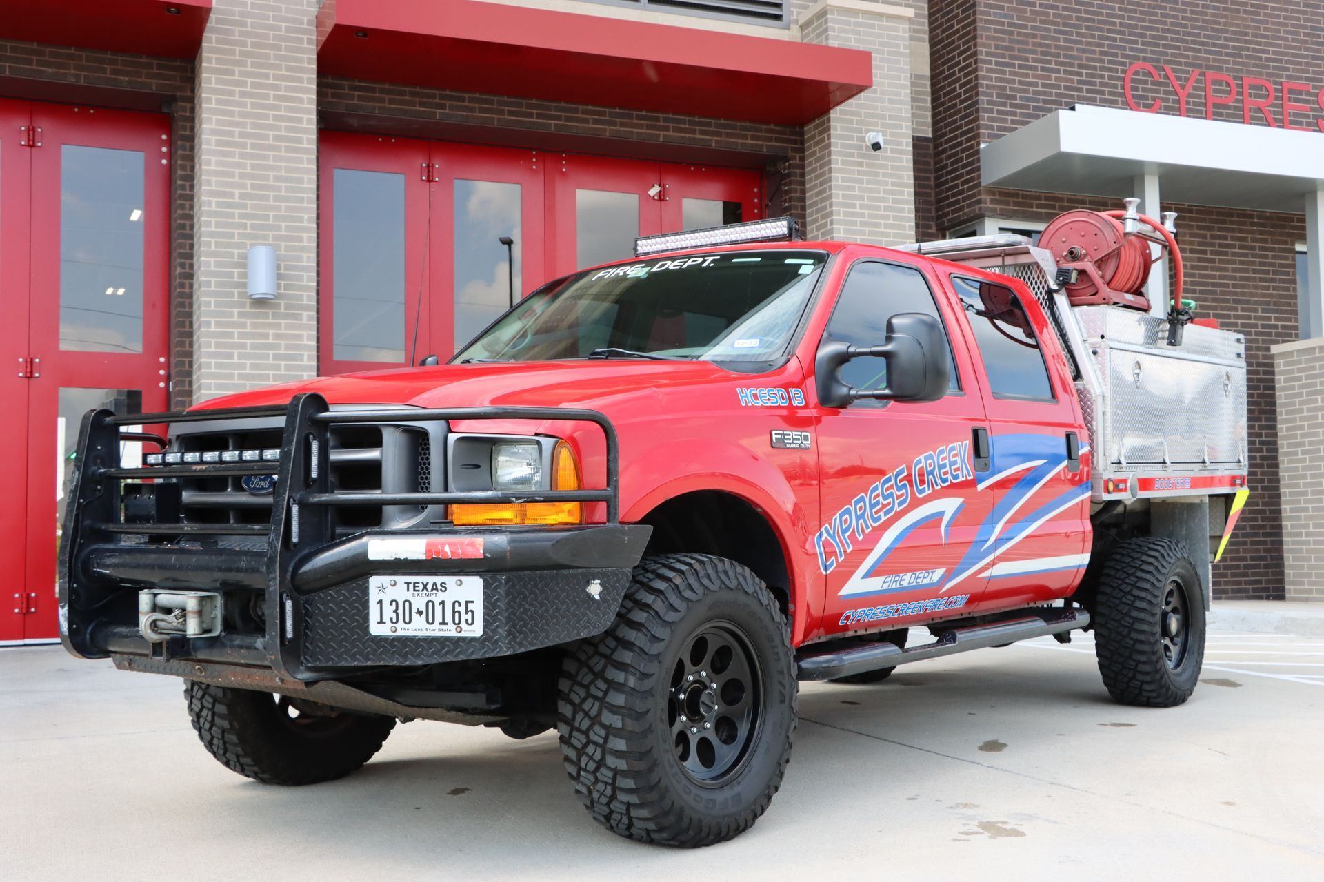 A red truck is parked in front of a fire station. Cypress Creek booster 25.