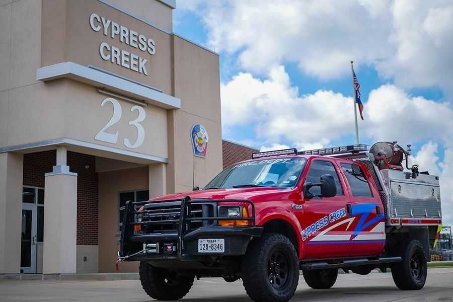 A red truck is parked in front of a building that says cypress creek. Cypress Creek Booster 23.