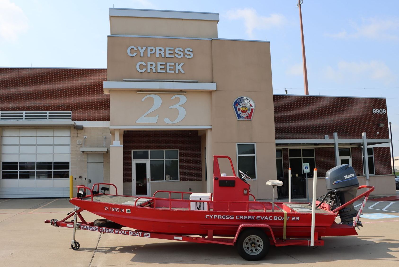 A red boat is parked in front of a cypress creek fire station. Evacuation Boat 23.