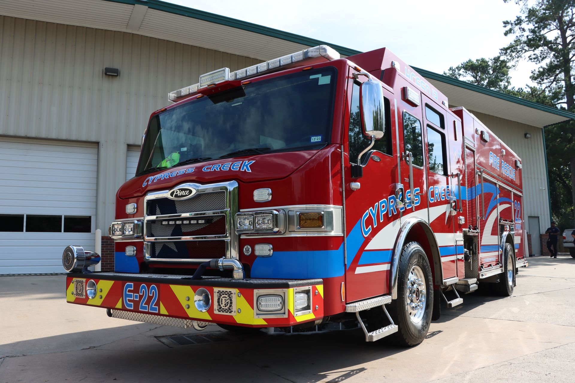 A red and blue fire truck is parked in front of a garage. Cypress Creek engine 22