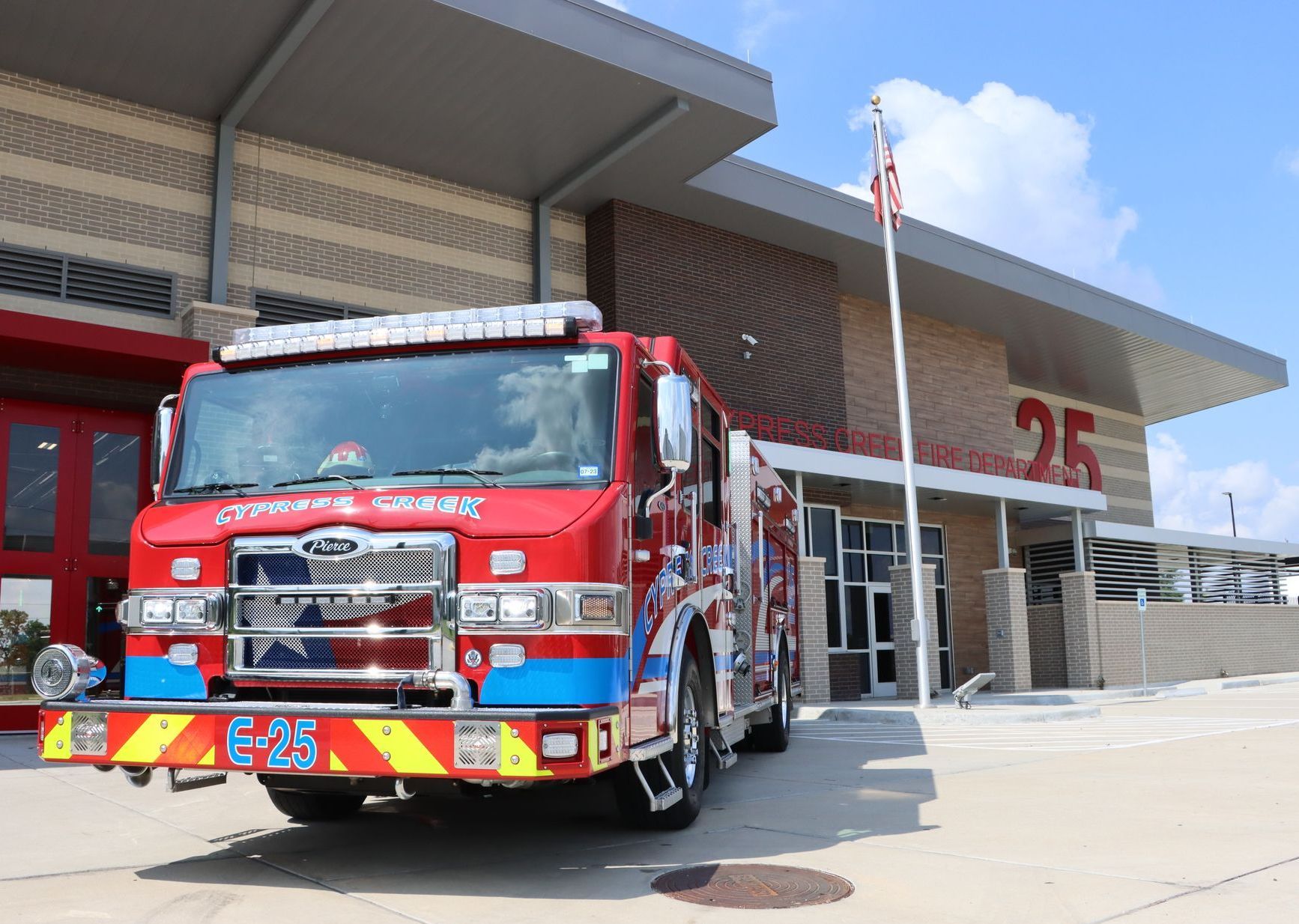 A red and blue fire truck is parked in front of a fire station. Cypress Creek engine 25.