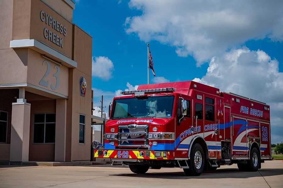A red fire truck is parked in front of a building. Cypress Creek engine 23.