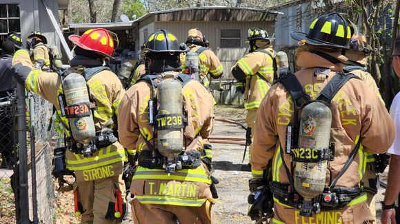 A group of firefighters are standing in front of a building. Links to Fire Safety page.