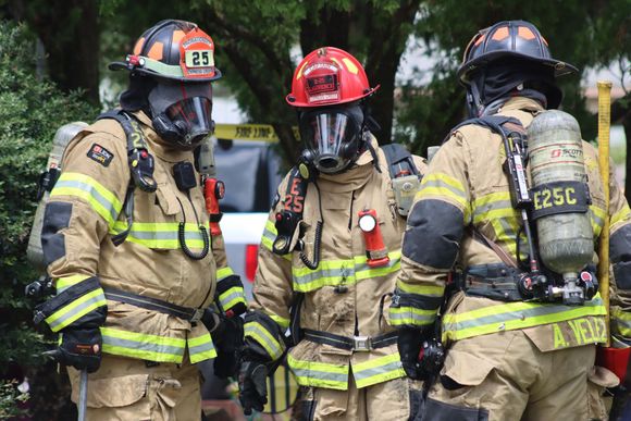 A group of firefighters are standing in front of a building. Links to Fire Safety page.