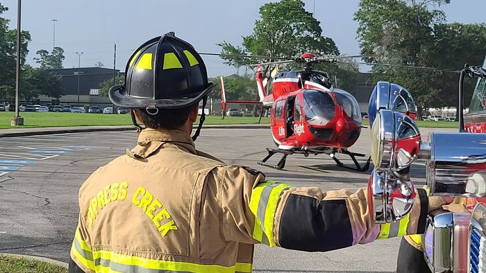 A fireman is pointing at a helicopter in a parking lot
