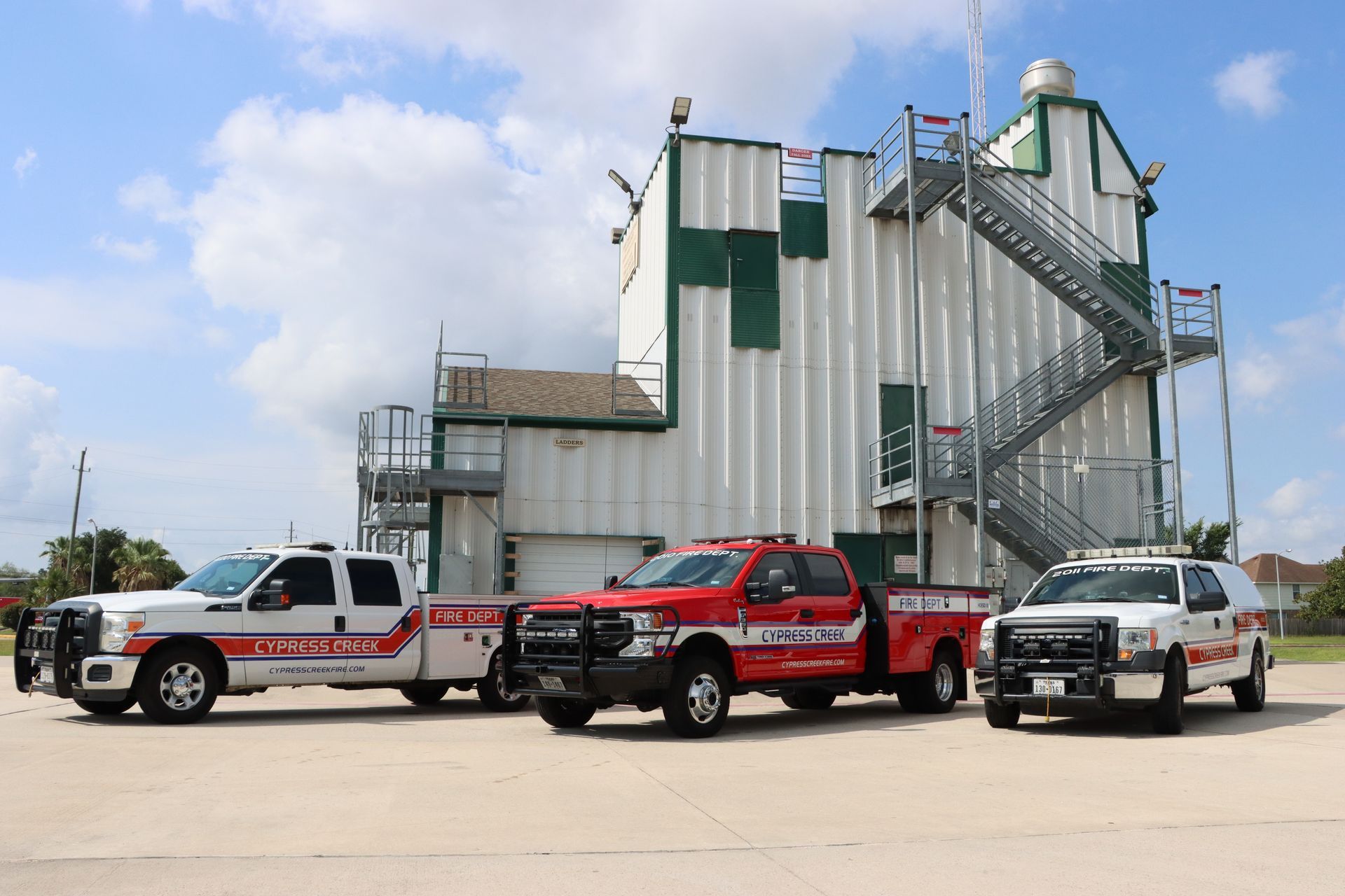 Three emergency vehicles are parked in front of a building. Cypress Creek Logistics fleet.