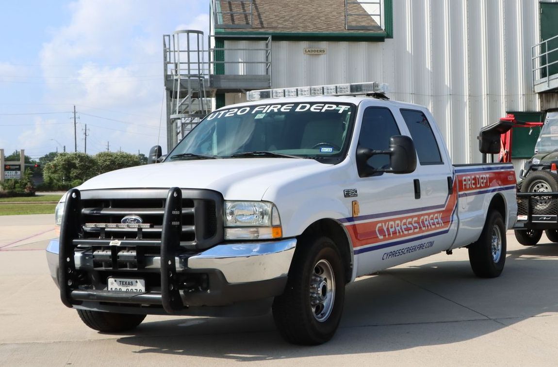 A white truck is parked in front of a building. Cypress Creek Utility Truck 20.