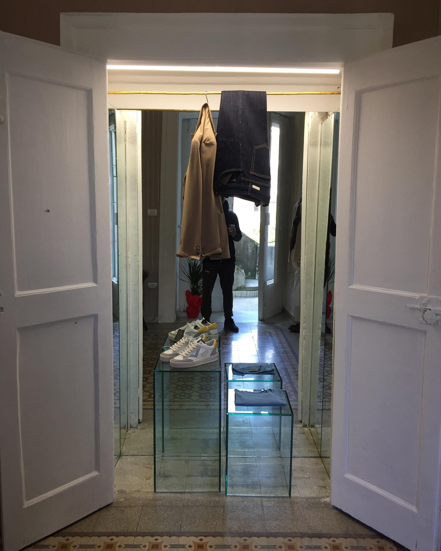 Aprendo le doppie porte bianche si accede a uno stretto corridoio dove sono appesi i cappotti e su un tavolo di vetro si trovano le scarpe.