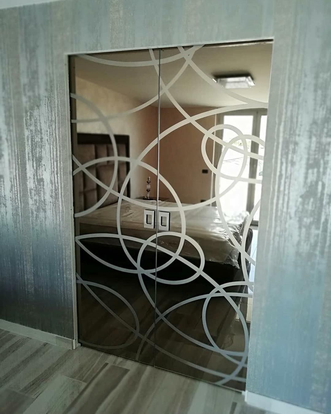 Pannello decorativo a specchio con motivo circolare in metallo che si apre su una zona notte.