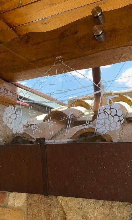 Delle decorazioni a forma di uccelli con le ali bianche sono appese davanti a una finestra con travi di legno e cielo azzurro.