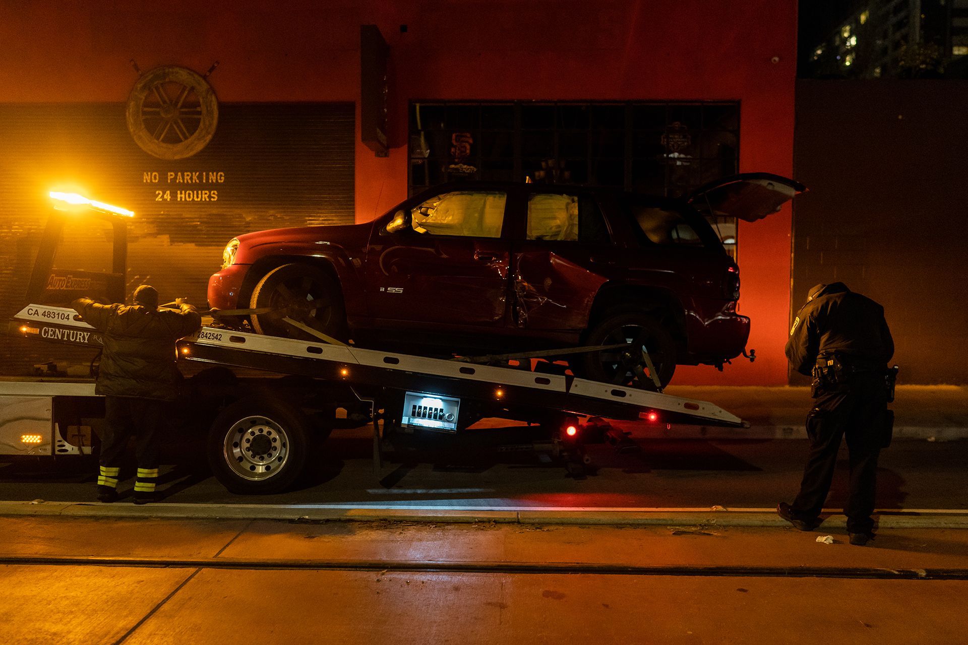 A red suv is being towed by a tow truck.