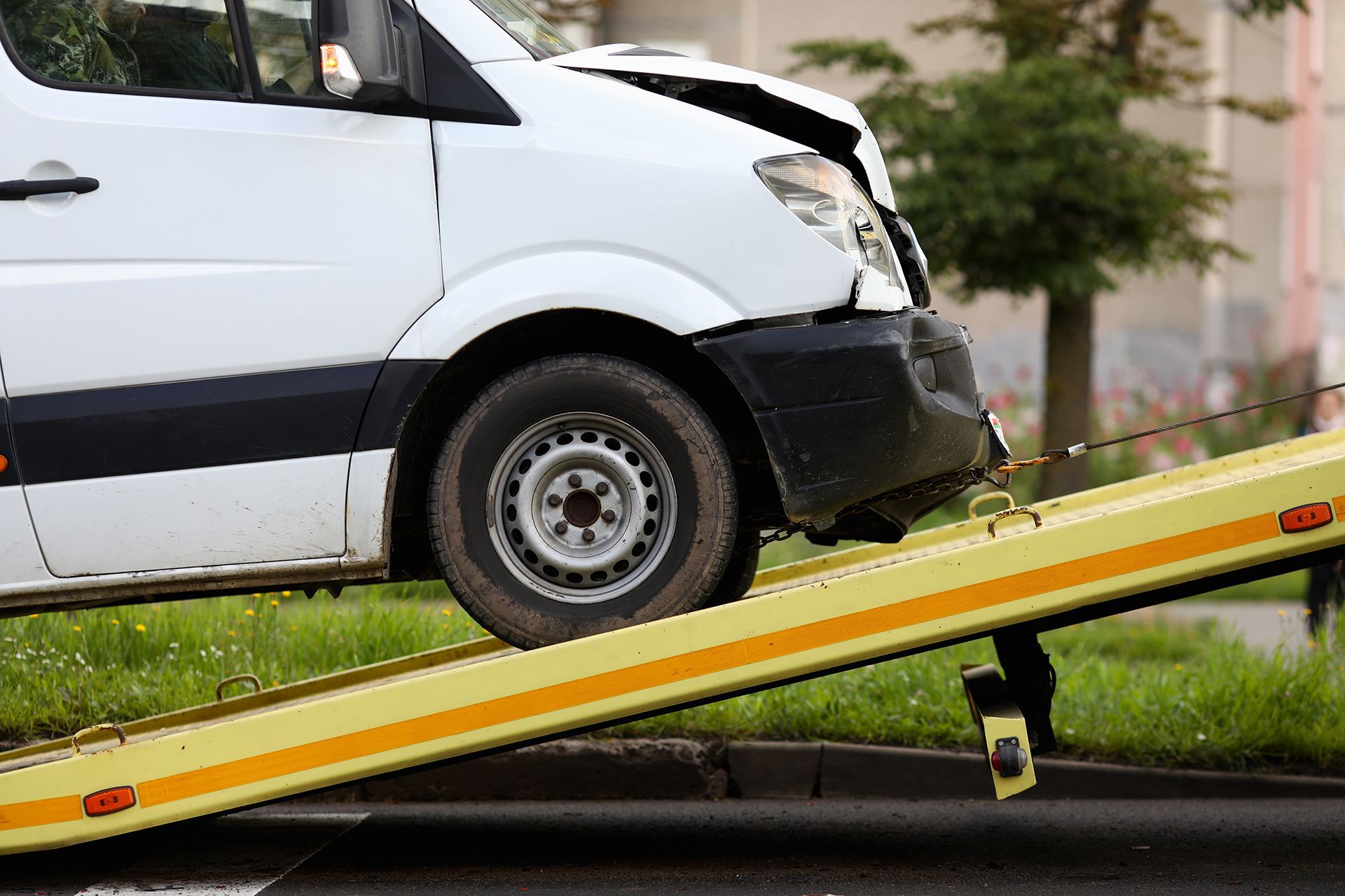 A white van is being towed by a tow truck.