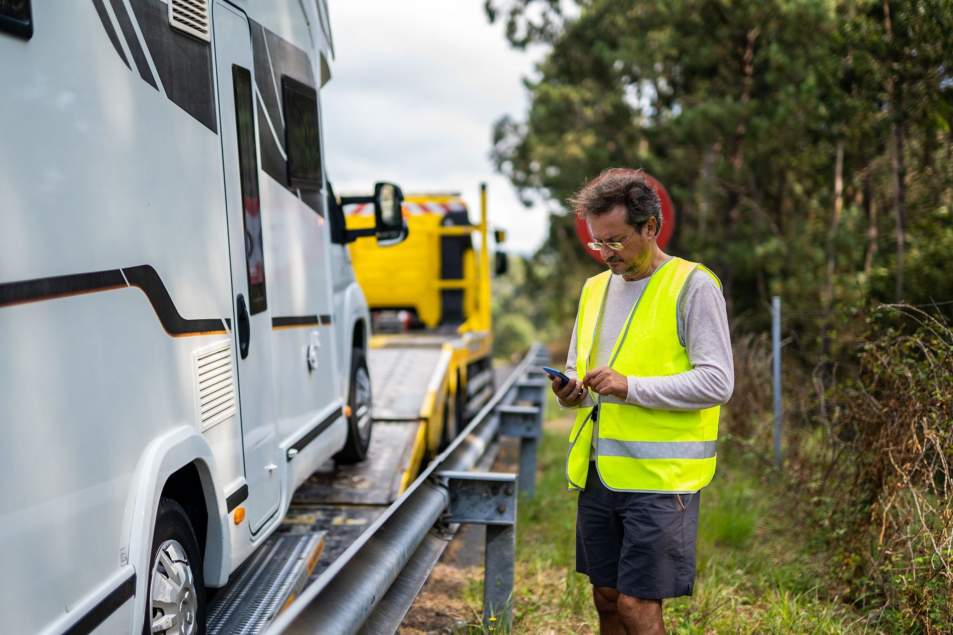 A man in a yellow vest is standing next to a rv.